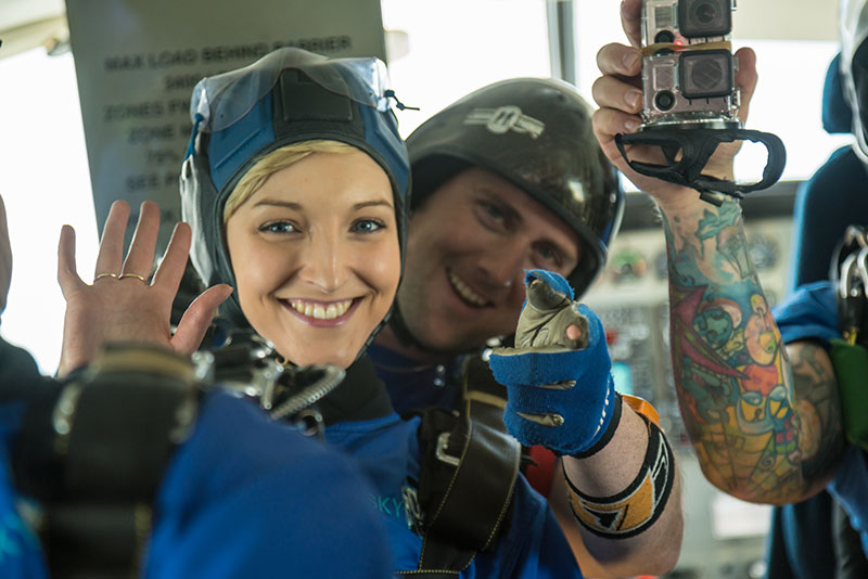 Skydivers on flight up smiling with camera.